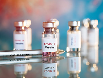 Mehrere Corona-Impfstoff-Fläschchen auf einem Tisch mit einer Spritze