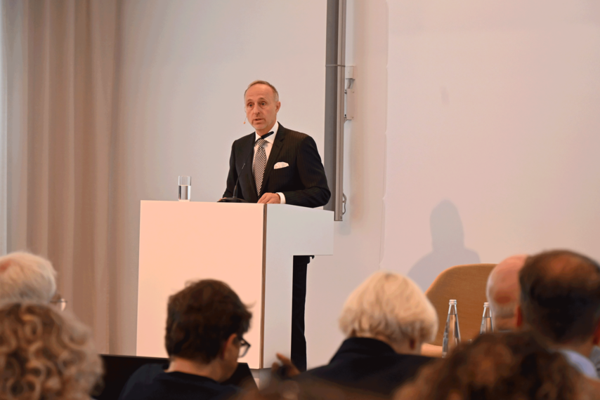 Ein Veranstaltungsraum. Dr. Stephan Hofmeister steht am Podium und hält eine Rede. 