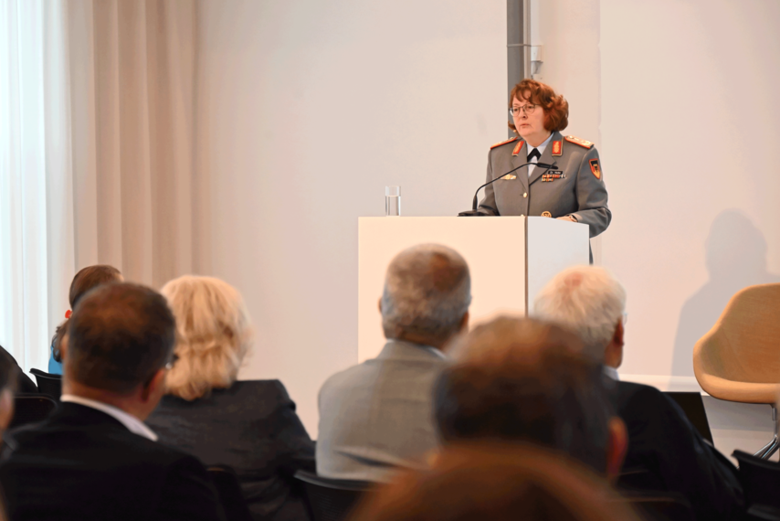 Ein Veranstaltungsraum. Dr. Almut Nolte  steht am Podium und hält eine Rede. 