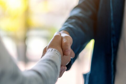 Zwei Hände werden geschüttelt. Unscharfer Hintergrund.