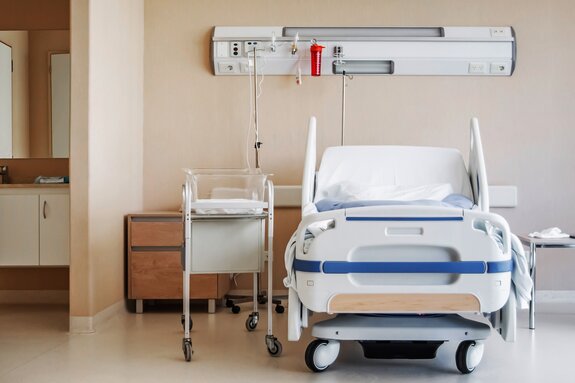 Blick auf ein Krankenbett mit einem Kinderbett in einem Patientenzimmer.