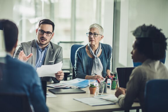 4 Personen am Tisch diskutieren