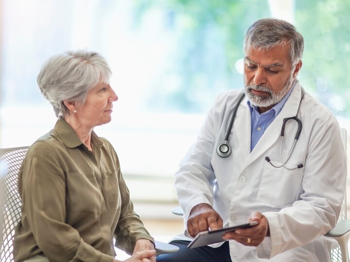 Arzt spricht mit digitalem Tablet mit Seniorin