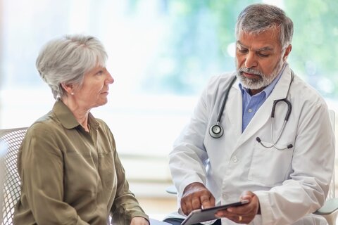 Arzt spricht mit digitalem Tablet mit Seniorin