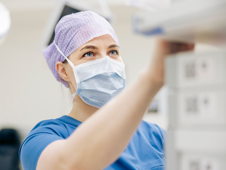 Eine Chirurgin in OP-Kleidung bedient ein medizinisches Gerät während einer ambulanten Operation.