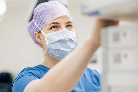 Eine Chirurgin in OP-Kleidung bedient ein medizinisches Gerät während einer ambulanten Operation.