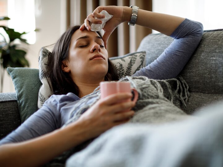 Frau liegt krank auf dem Sofa
