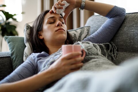 Frau liegt krank auf dem Sofa
