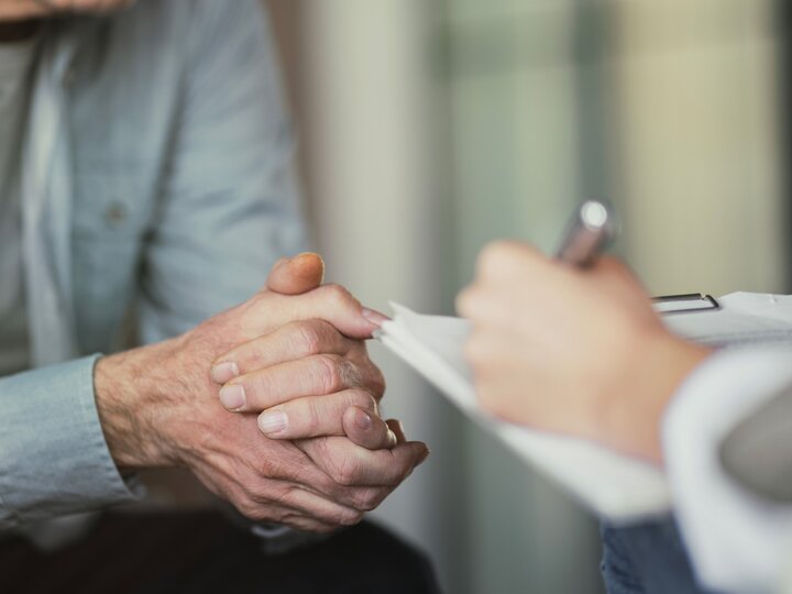 Ausschnitt: Arzt spricht mit Patient und macht sich Notizen