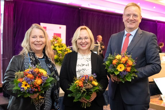 Drei Personen halten Blumensträuße und lächeln in die Kamera: Dipl.-Psych. Anke Pielsticker, Dr. Petra Reis-Berkowicz, Dr. Rolf Englisch