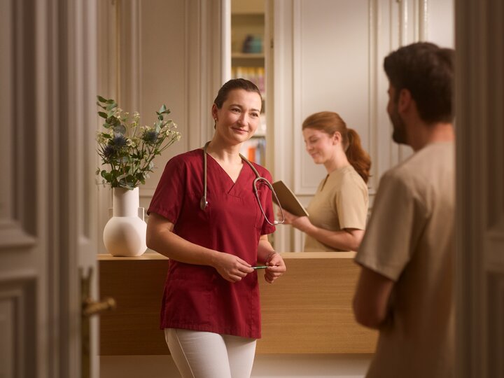 Ärztin in einer Praxis. Im Hintergrund der Empfangstresen.